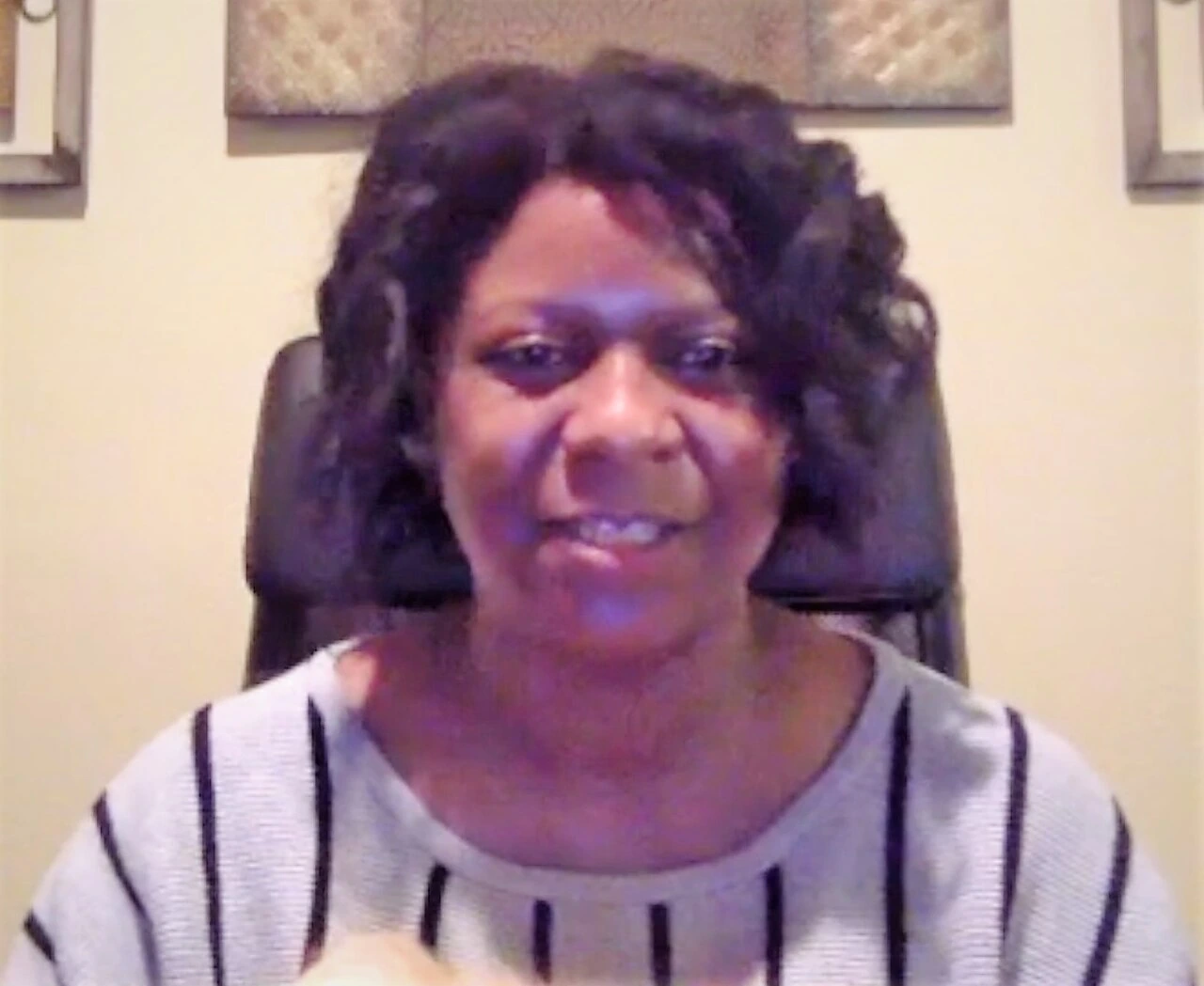 Apryl Michelle Brown speaking in a video-call style portrait, seated indoors against a light background.