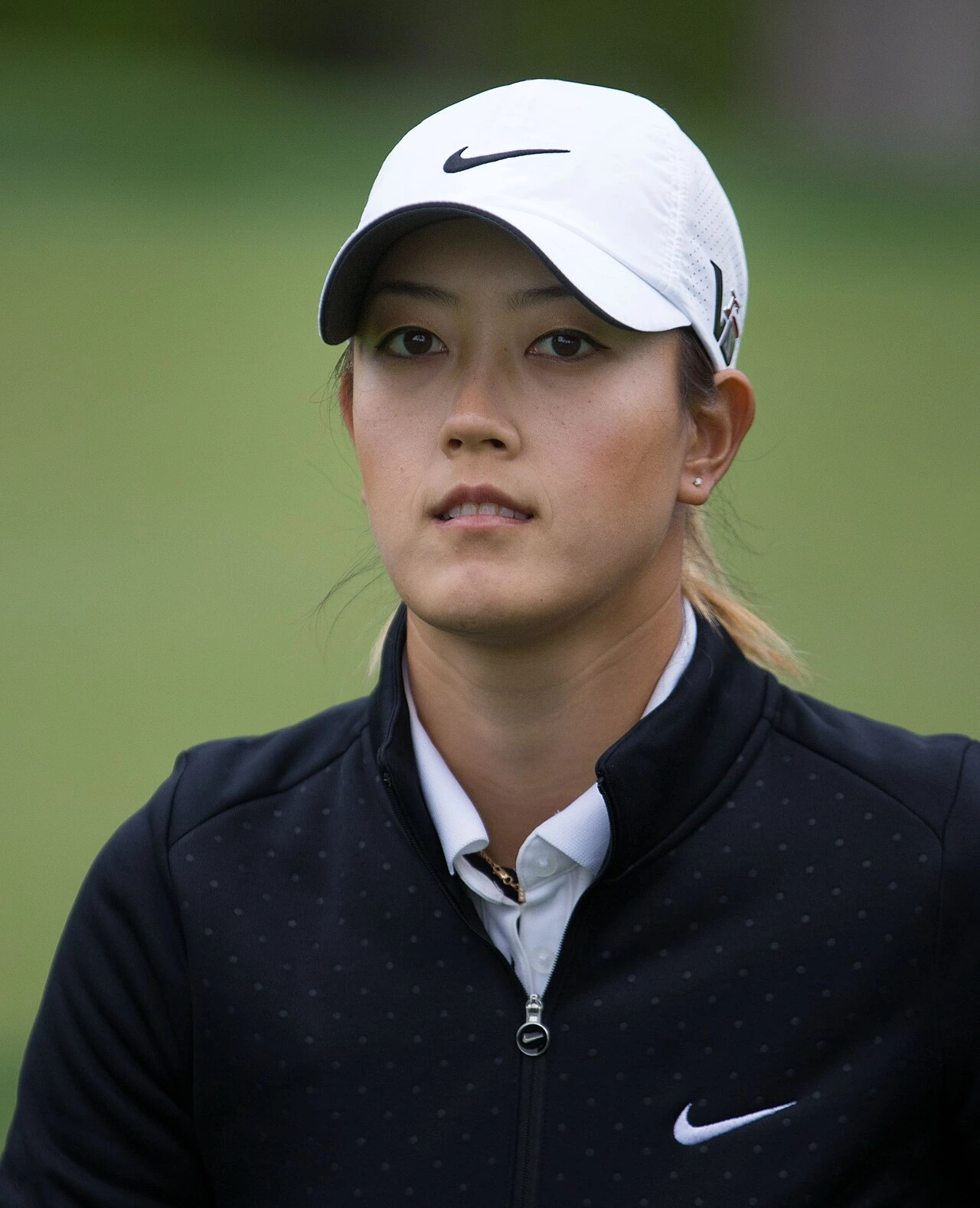 Michelle Wie West in a golf cap and jacket on the course