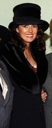 Michelle Rocca wearing a black hat and coat, smiling at an event.