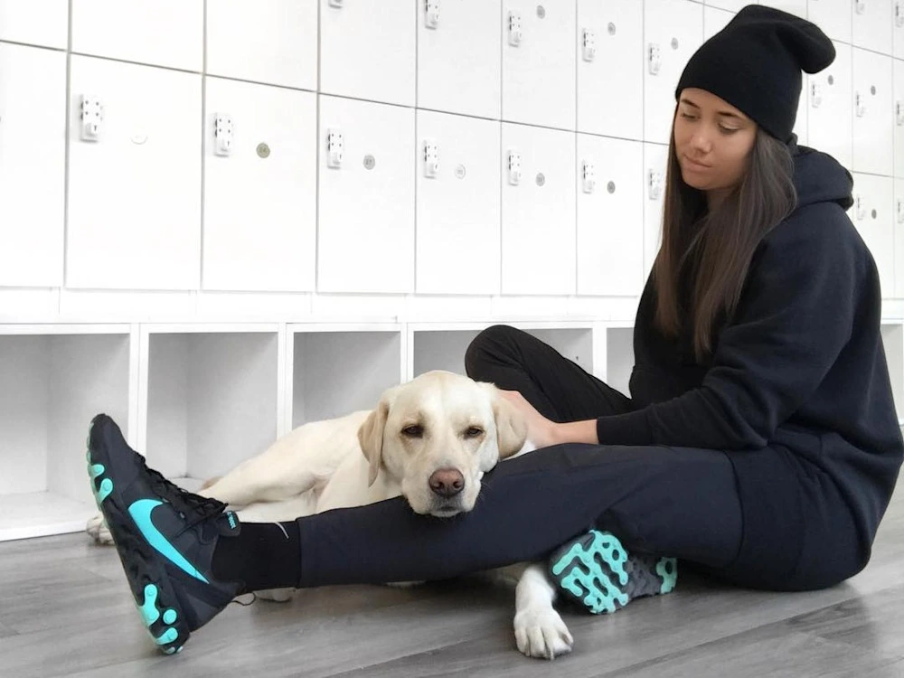 Michelle August sitting with a dog in a locker room or studio setting