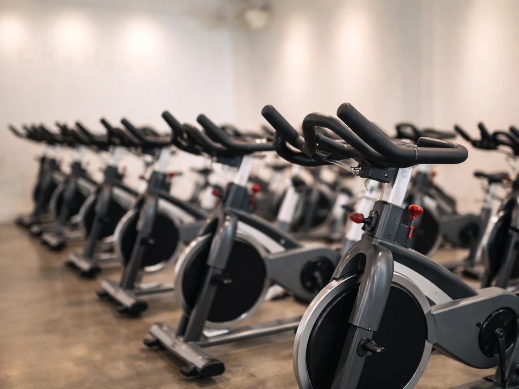 Empty spin studio with modern stationary bikes and blurred branding-style signage in the background.