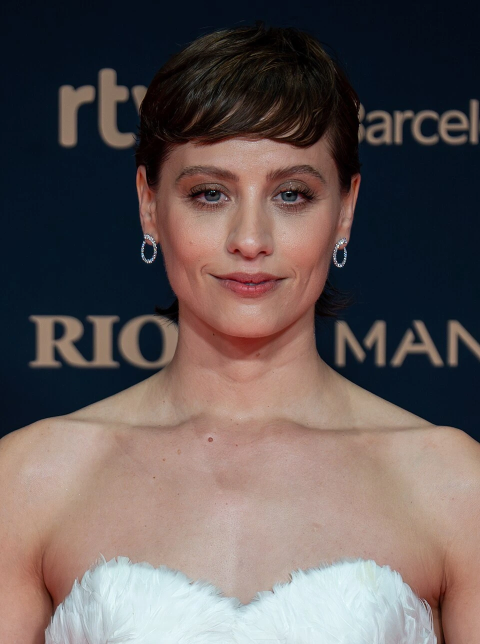 Michelle Jenner at a red carpet event, photographed in a close-up portrait against a branded backdrop.