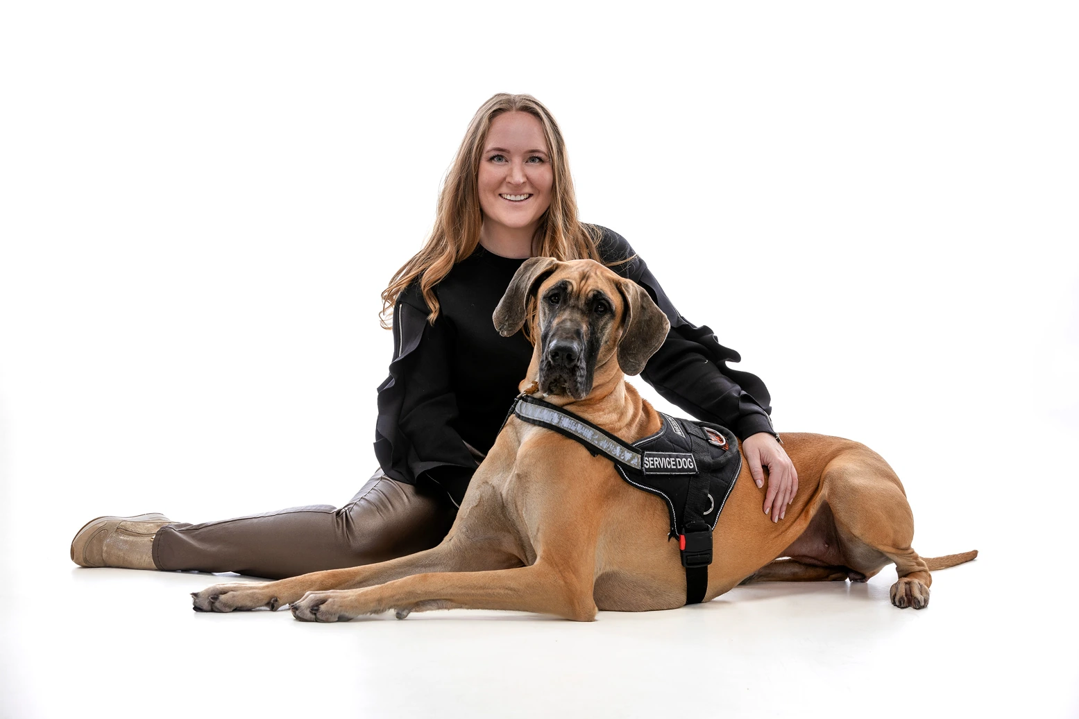 A woman sitting with a large dog in a studio-style portrait on a white background.